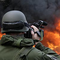Caméraman militaire filmant un bâtiment en flammes