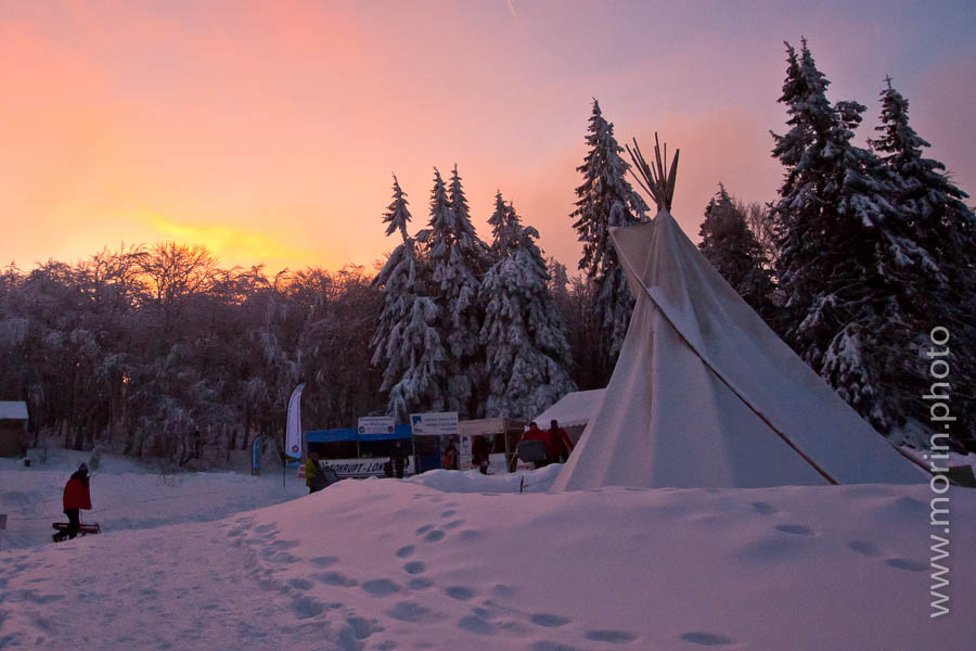 lever de soleil sur un tipi au milieu d'une forêt enneigée